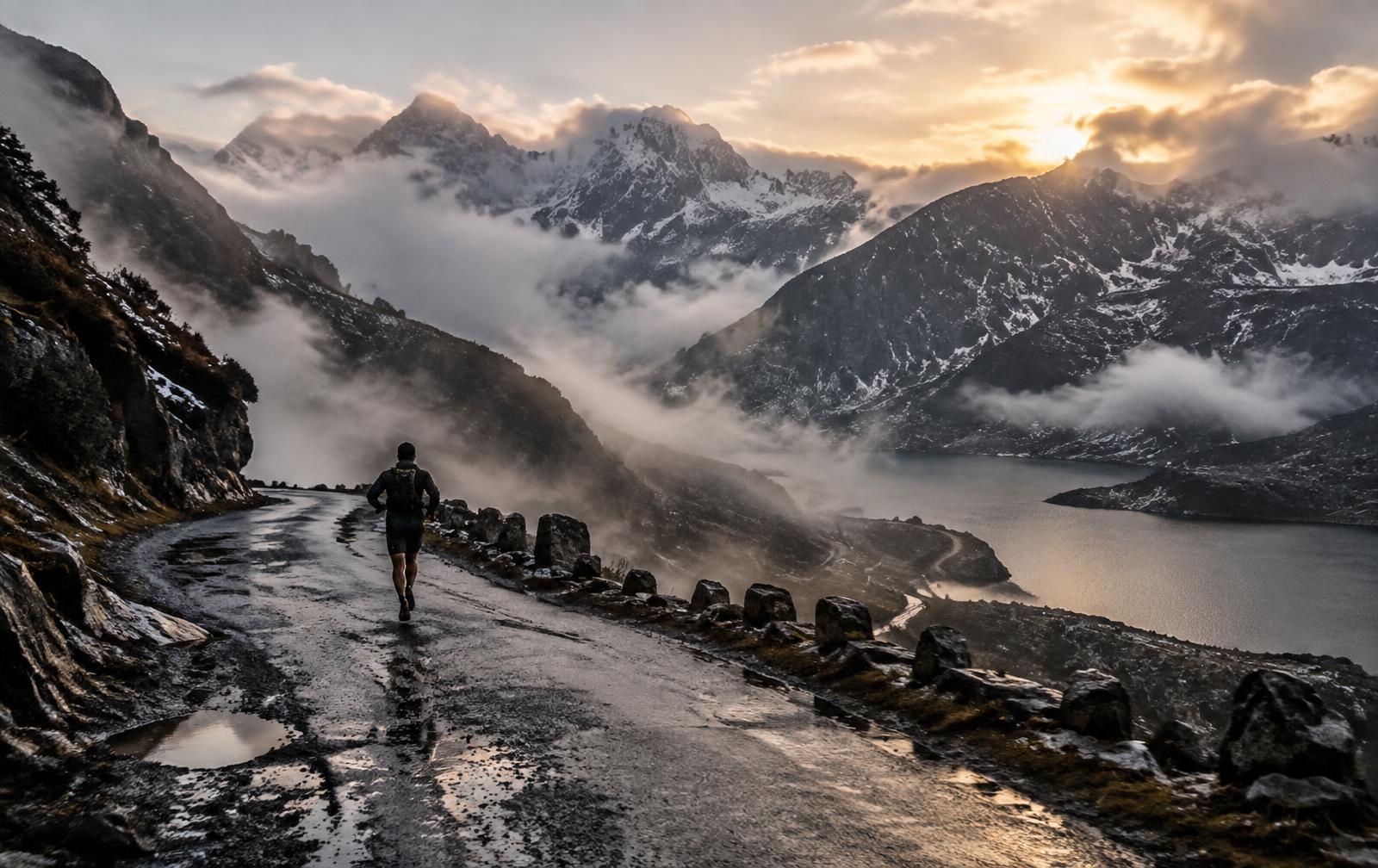 A lone runner on a wet Himalayan mountain road above a high-altitude lake